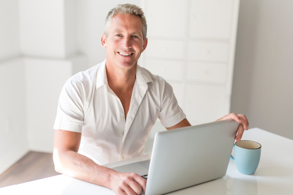 Mature Man Using Laptop On Desk At Home